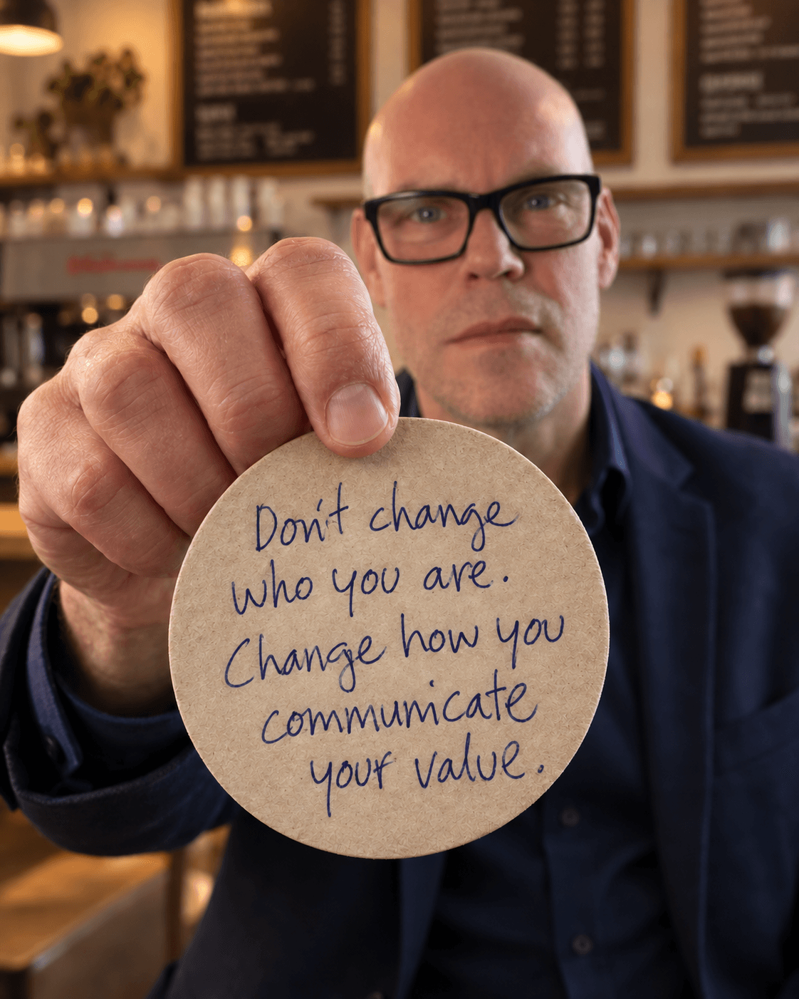 Thom Bouman holding a coaster that reads: Don't change who you are. Change how you communicate your value.